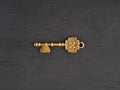 Bronze antique key with two heart shaped holes on black wooden background Royalty Free Stock Photo