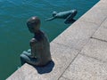 Bronze boy figurines playfully situated at the waters edge
