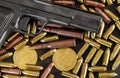 Bronze and brass gun bullets scattered on dark table, black pistol barrel, golden bitcoin coins near - illegal use of