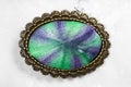 Bronze brooch with hand-colored silk batik on gray Royalty Free Stock Photo