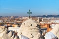 Bronze christian cross faces a Rome out of focus Rome panorama