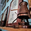 A bronze coffee pot with a wooden handle stands on a shelf