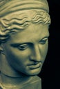 Plaster sculpture of woman face. Bronze color gypsum copy of ancient statue of Diana head for artists on black