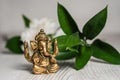 Bronze Ganapathi Ganesha Idol decorated with white flowers and green leaf in background