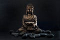 Bronze Gautama Buddha with Dark Rocks Isolated on Black