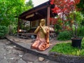 Bronze Gautama Buddha decorative statue in a garden under red ma