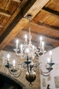 Bronze glowing chandelier with spheres and candle lamps hangs from a wooden ceiling