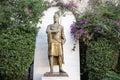 Bronze greek statue on pedestal in green bushes and flowers Royalty Free Stock Photo