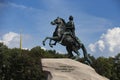 Bronze Horseman equestrian sculpture of Peter the Great side view, with the Admiralty spire, blue sky and white clouds background