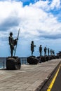 Large tall bronze statues along the ocean shore on the island