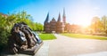 Bronze Lion statue in front of Holsten Gate - Panoramic shot of Holstentor and park, a city gate marking off the western Royalty Free Stock Photo