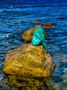 Bronze mermaid sculpture called Sirenella di L`Isula Rossa sitting on a rock in the Mediterranean Sea Royalty Free Stock Photo