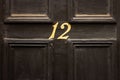 House number 12 on a black dusty front door in Britain