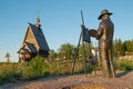 Bronze monument to Russian artist Isaac Levitan standing in front of an easel on old wooden Orthodox church background