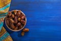 Bronze plate with dates on old blue wooden table. Ramadan background. Flat lay