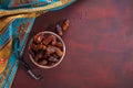 Bronze plate with dates and tasbih misbaha on old red-brown wooden table. Ramadan background. Flat lay. Selective focus