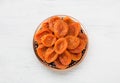 Bronze plate with dried apricots on the white wooden table. Top view