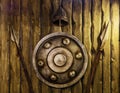 A bronze shield helmet and spears hang on a wooden wall. Knight armour. Decor in medieval style