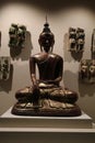 Bronze statue of The Buddha sitting on a plinth.