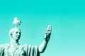 Statue of emperor Caesar Nervae August with gull on the head. Man taking selfie. Humor concept. Cyan color background Royalty Free Stock Photo