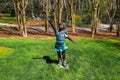 A bronze statue of a little girl holding a butterfly surrounded by lush green grass, trees and plants at Gibbs Gardens