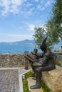 Bronze statue, soldier reading boy from book, in Torri del Benaco