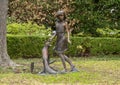 Bronze statue of a young barefooted girl petting a fox in a yard in Dallas, Texas