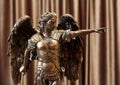 A bronze statuette of the Archangel Michael points a finger forward