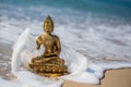 Bronze statuette Buddha on the beach with waves