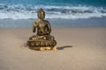 Bronze statuette Buddha on the beach with waves Royalty Free Stock Photo