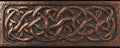A bronze textured surface with intricate, Celtic knotwork patterns engraved into the metal, adding Royalty Free Stock Photo