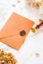 Bronze wedding envelope, wax seal stamp, dry grass on marble desk table Royalty Free Stock Photo