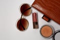 Bronzer, sunglasses and lip gloss dropping out from a female purse Royalty Free Stock Photo