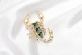 Brooch gold scorpion on white silk Royalty Free Stock Photo