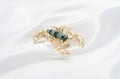 Brooch gold scorpion on white silk Royalty Free Stock Photo