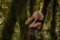 Brooding dreamy young girl blonde, black dress with a hood standing by a tree Royalty Free Stock Photo