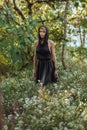 Brooding dreamy young girl blonde, black dress with a hood standing by a tree Royalty Free Stock Photo