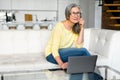 Brooding middle-aged woman using a laptop for remote work at home