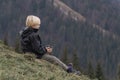 Brooding young boy sits on hillside with cup of tea and looking at the distance. Child in mountains. Travel outdoor