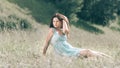 Brooding young woman sitting on the grass of a summer meadow.