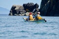 Two people in a kayak paddle near rocky shore on sunny day near the Brookes Peninsula