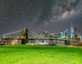 The Brooklyn Bridge with milky way with Manhattan skyline on background and green meadow in foreground, New York City Royalty Free Stock Photo