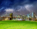 The Brooklyn Bridge during a storm with Manhattan skyline on background and green meadow in foreground, New York City Royalty Free Stock Photo