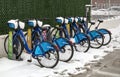 Citibike NYC bike share bicycles docked in their charging stations covered in snow during winter in Brooklyn, New York City.