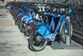 Long row of Citibike corporate sponsored bike share bicycles docked in a dock bay on a street in New York City.