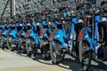 Long row of Citibike corporate sponsored bike share bicycles docked in a dock bay on a street in New York City.