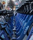 Long row of Citibike corporate sponsored bike share bicycles docked in a dock bay on a street in New York City.