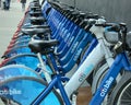 Long row of Citibike corporate sponsored bike share bicycles docked in a dock bay on a street in New York City.