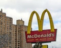 McDonald\'s fast food restaurant sign with golden arches in front of a tall high rise building in Brooklyn, New York City.