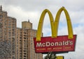 McDonald\'s fast food restaurant sign with golden arches in front of a tall high rise building in Brooklyn, New York City.